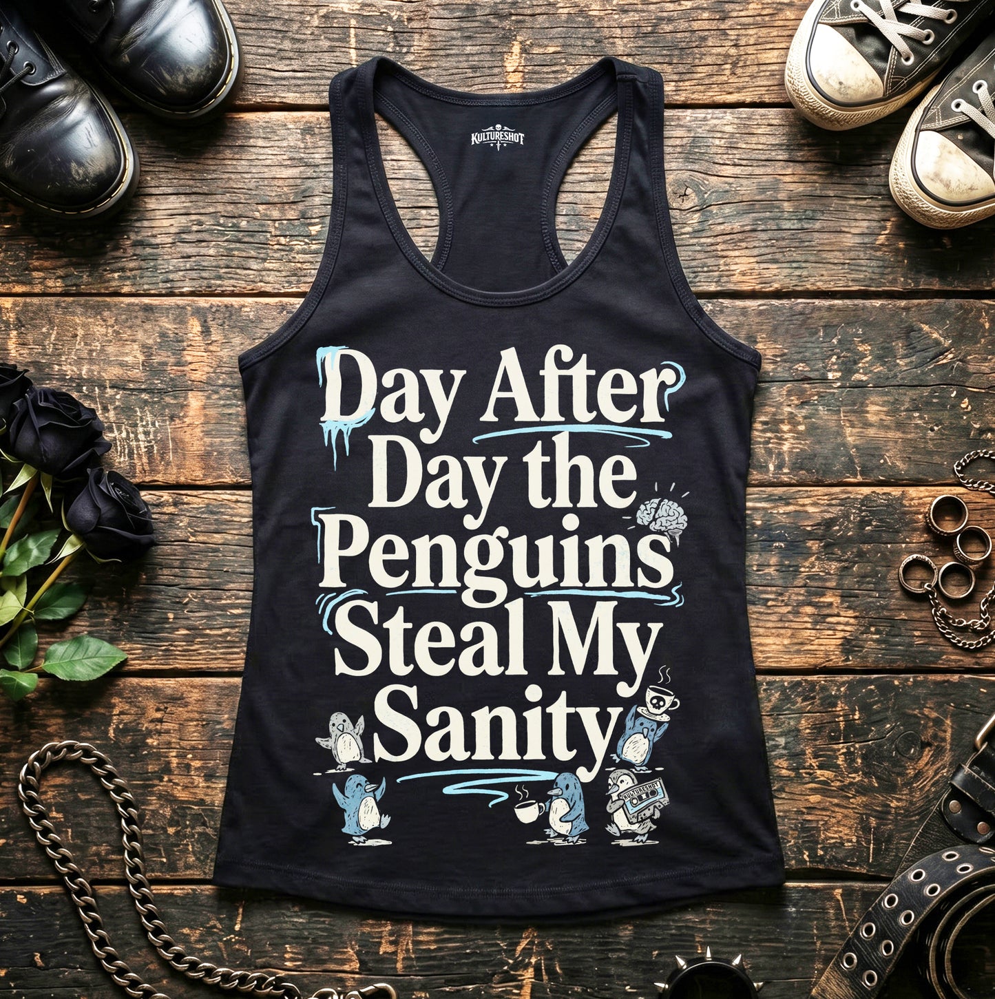 Black tank top with humorous text design on a wooden surface with shoes and accessories.