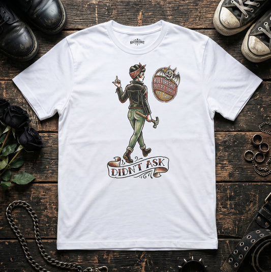 White t-shirt with graphic design on a wooden surface with shoes and accessories.