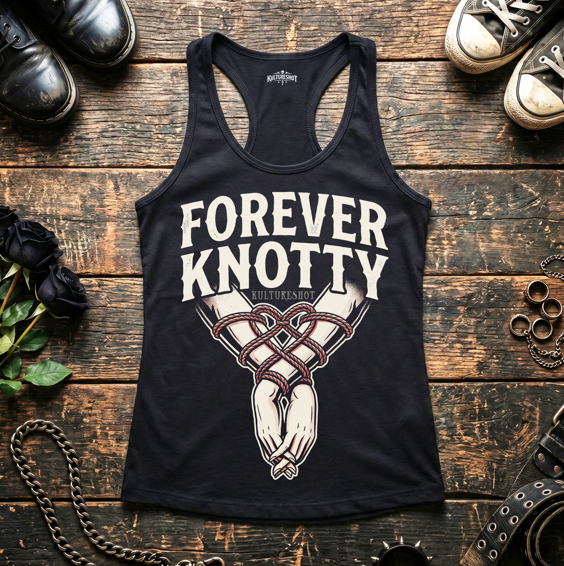 Black tank top with 'Forever Knotty' design on a wooden surface with shoes and jewelry.