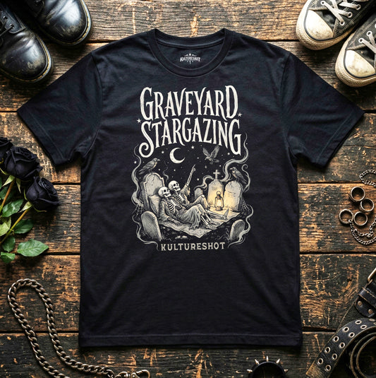 Black t-shirt with 'Graveyard Stargazing' graphic on a wooden surface with shoes and roses.