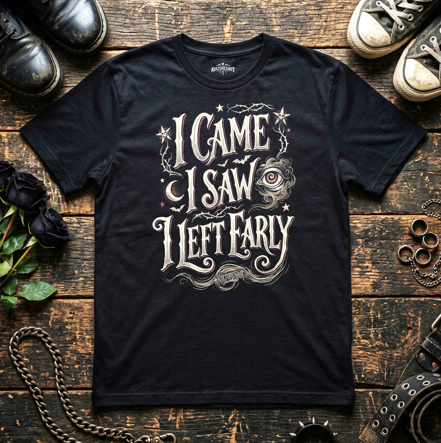 Black t-shirt with decorative text and design on a wooden surface with shoes and chains.