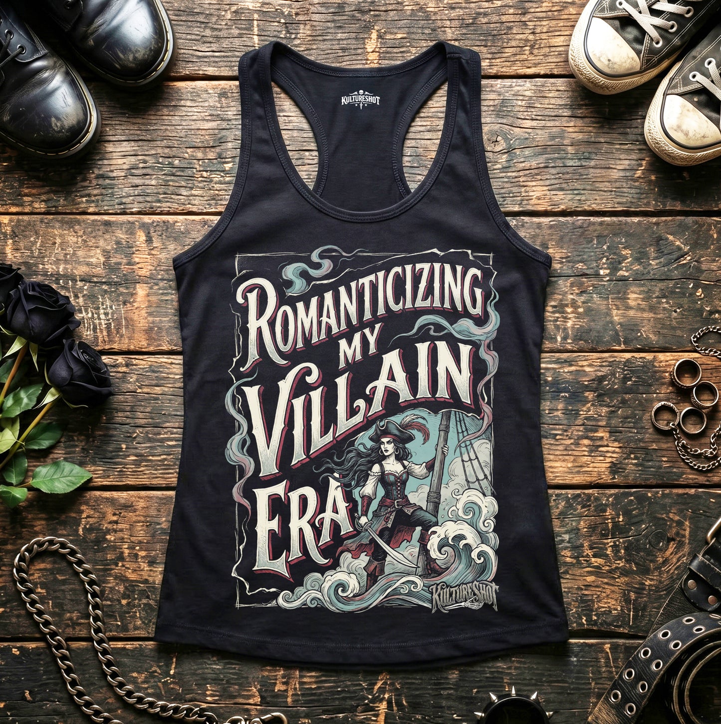 Black tank top with graphic design and text on a wooden surface with shoes and decorative items.