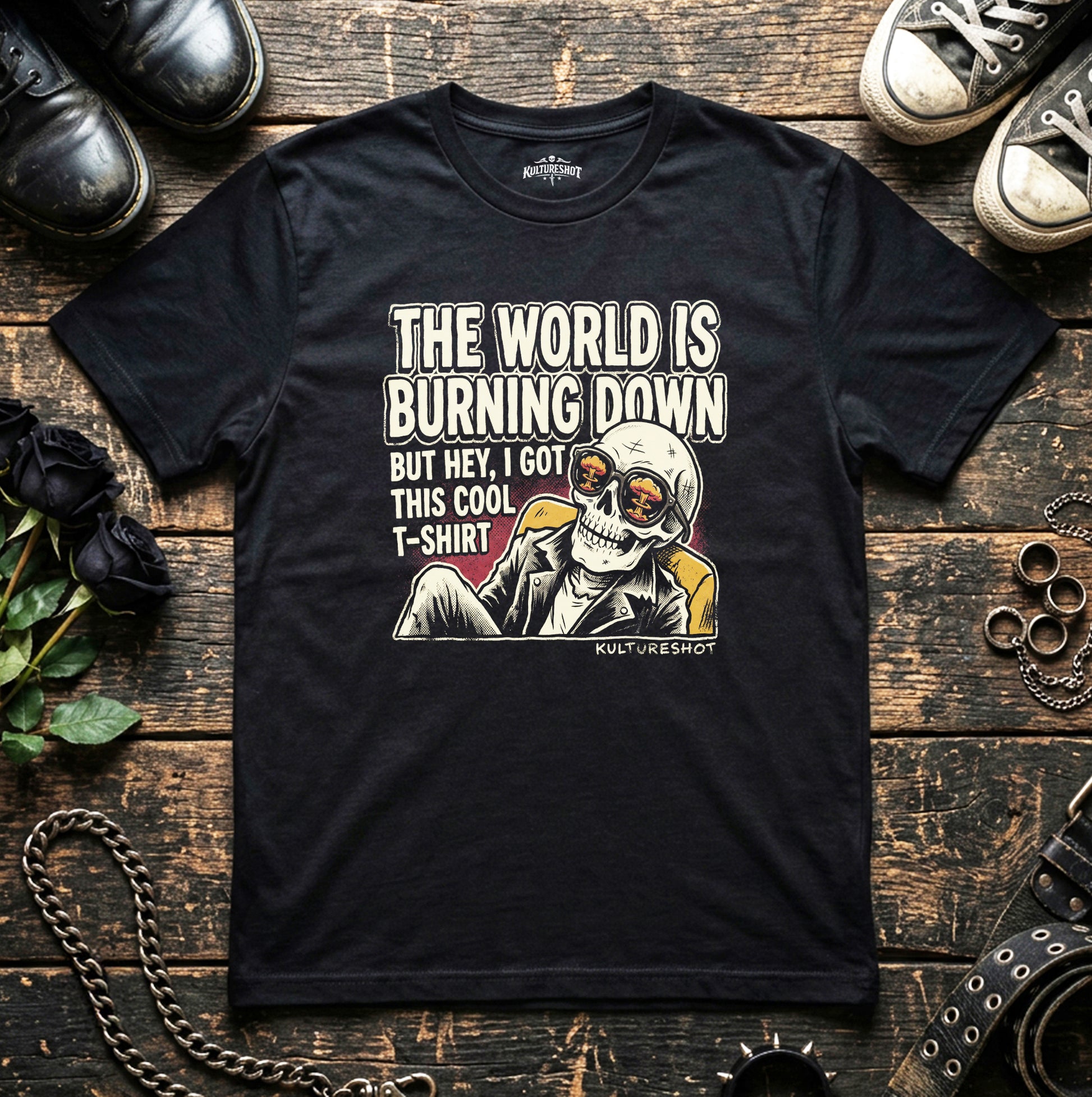 Black t-shirt with graphic design and text on a wooden surface with shoes and accessories.